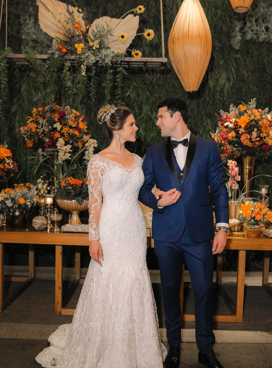 Casal ao lado da mesa do bolo com decoração de casamento
