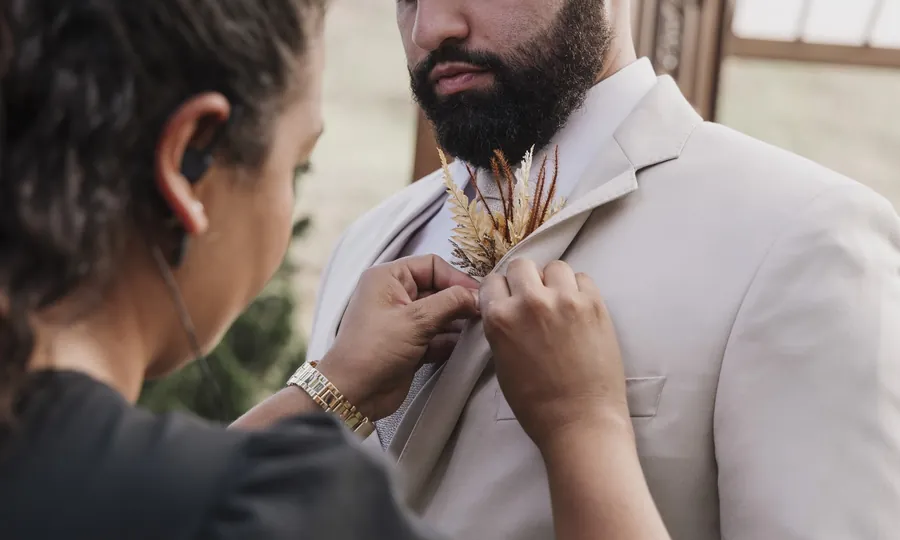 Cerimonialista arrumando o traje do noivo antes do casamento