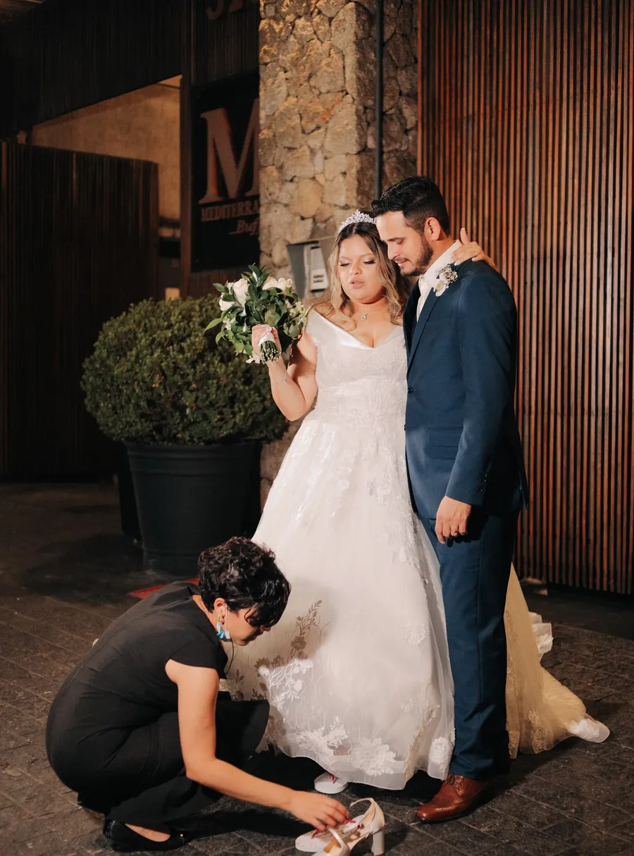 Equipe de cerimonial ajustando o sapato da noiva no dia do casamento