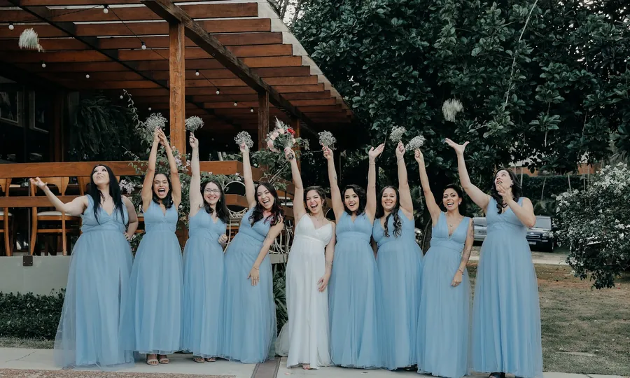 Madrinhas de azul celebrando com o buquê no casamento